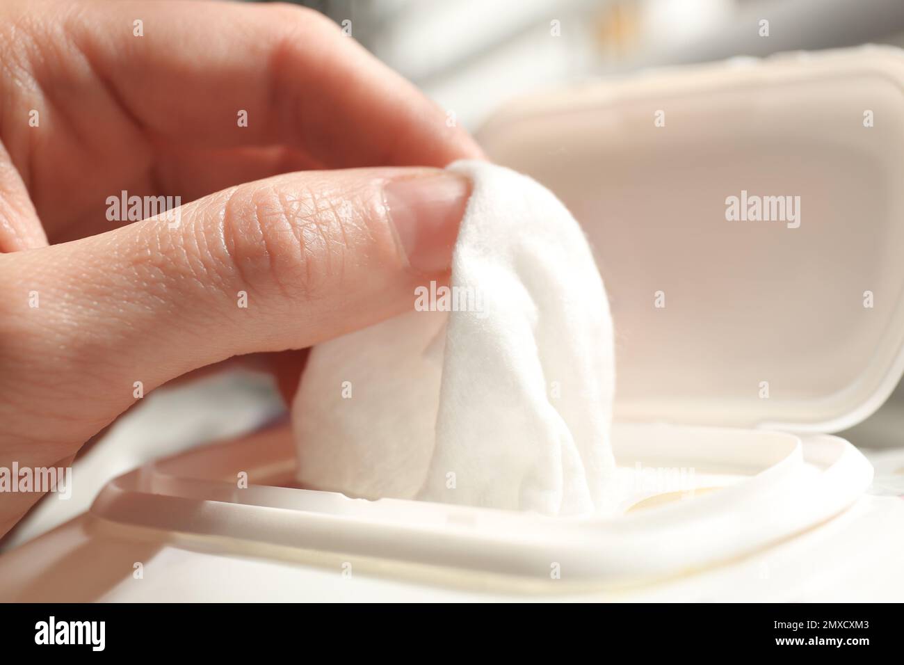 Woman taking wet wipe from pack on blurred background, closeup Stock