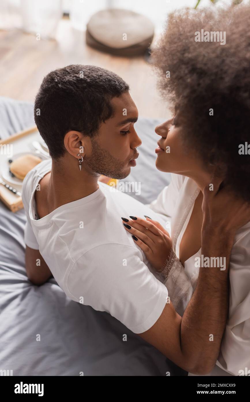 high angle view of african american man touching sexy girlfriend during breakfast on bed Stock Photo