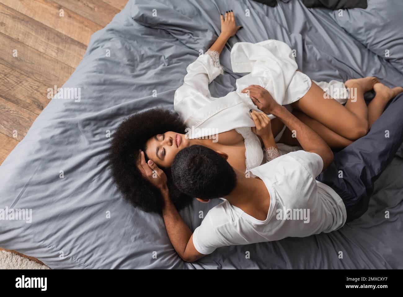 top view of african american man touching passionate girlfriend lying in white robe and sexy underwear Stock Photo