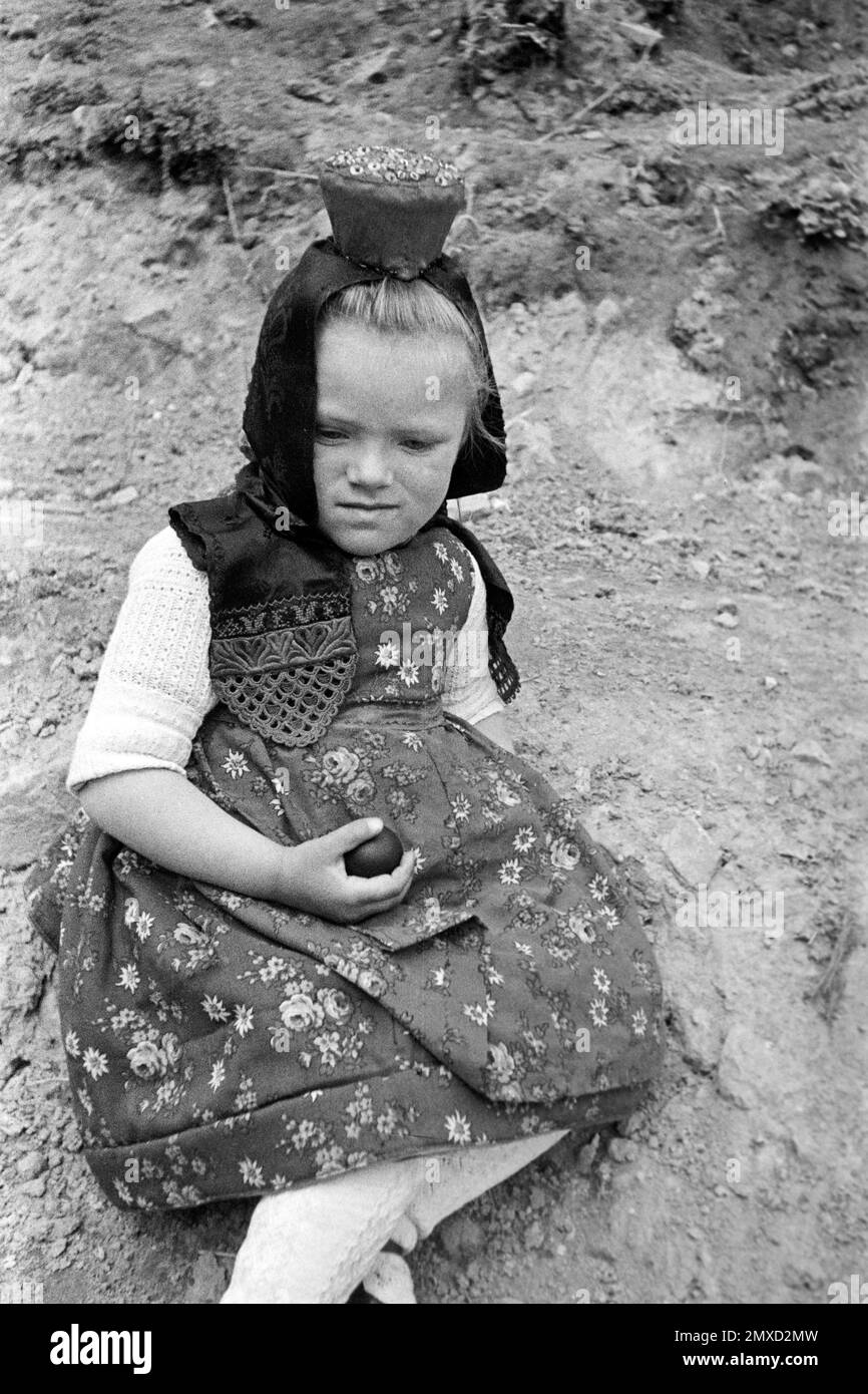 Mädchen mit Tracht und bemaltem Osterei in der Hand, Schwalm-Eder-Kreis in Hessen, 1938. Girl with traditional dress and painted Easter egg in her hand, Schwalm-Eder region in Hesse, 1938. Stock Photo