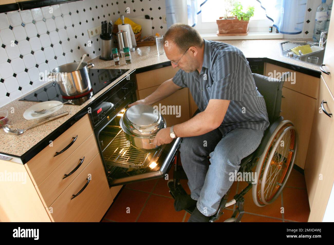 wheelchair user putting a roasting dish in the oven Stock Photo