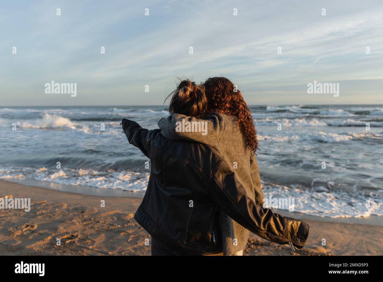 Back view of woman hugging friend on beach in Barcelona Stock Photo