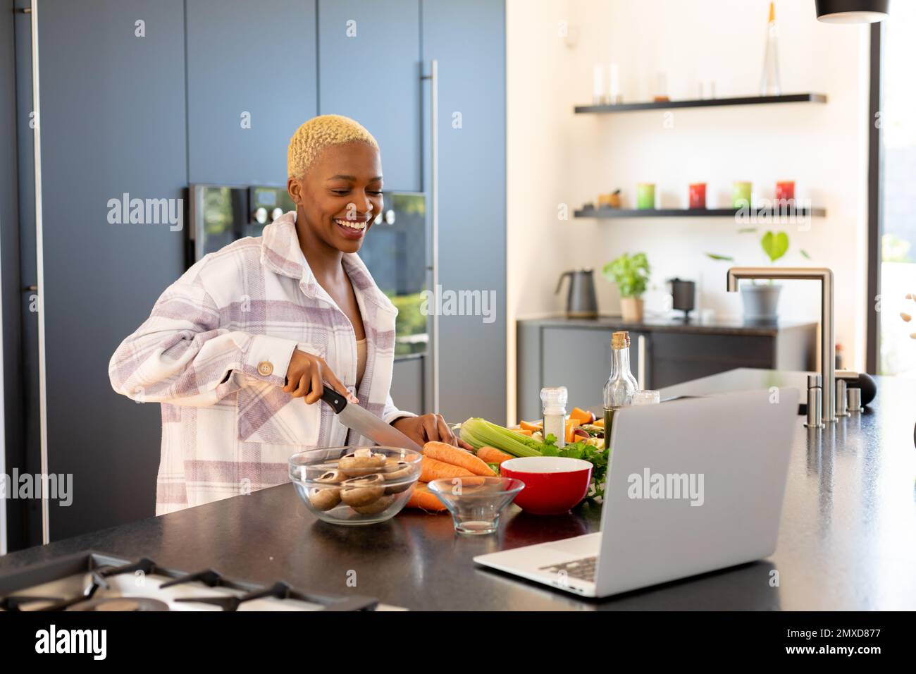 Happy african american woman cooking in kitchen, using laptop Stock ...