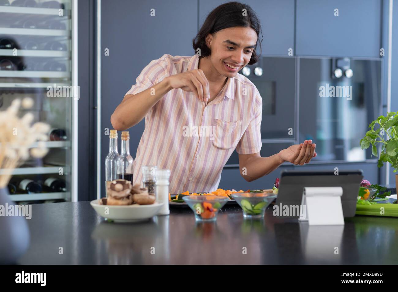 Happy biracial man cooking and using tablet in kitchen Stock Photo