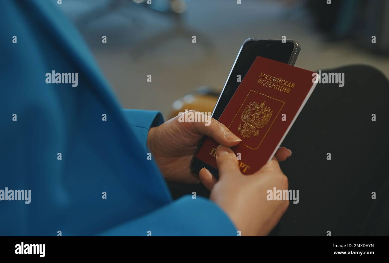 Woman with Russian Federation passport is waiting for her flight at the airport. Stock Photo