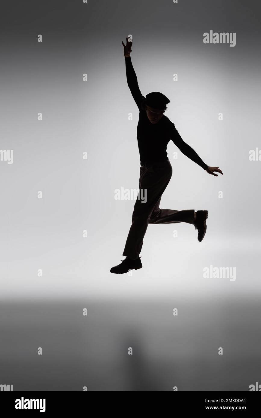dark silhouette of young african american man jumping on grey background,stock image Stock Photo