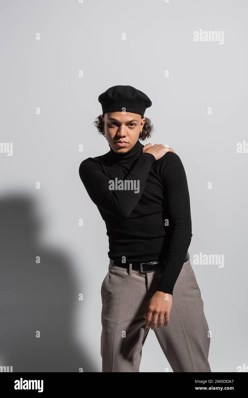 african american man in fashionable beret and black turtleneck posing with  hand on shoulder on grey background,stock image Stock Photo - Alamy