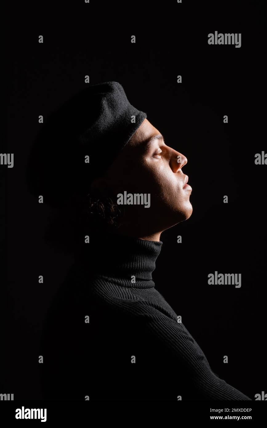 side view of fashionable african american man in turtleneck and sweater isolated on black,stock image Stock Photo