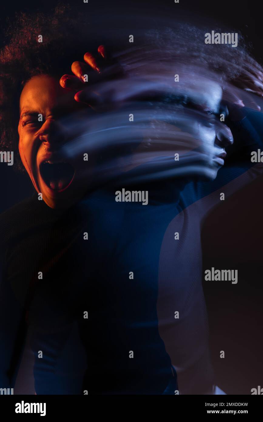 double exposure of irritated african american man with bipolar disorder screaming on dark background with orange and blue light,stock image Stock Photo