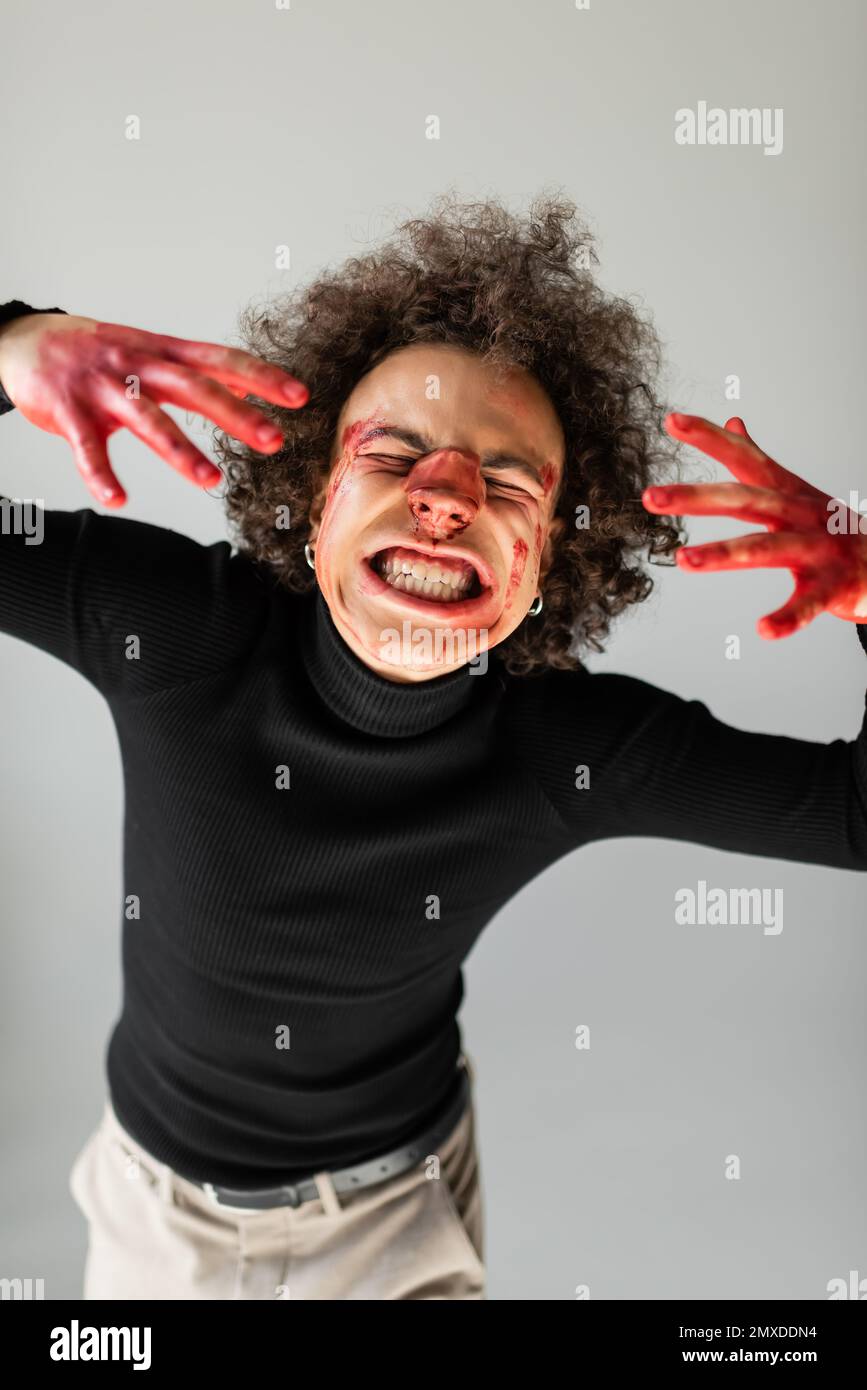 abused and injured african american man with bleeding face and broken nose grimacing isolated on grey,stock image Stock Photo