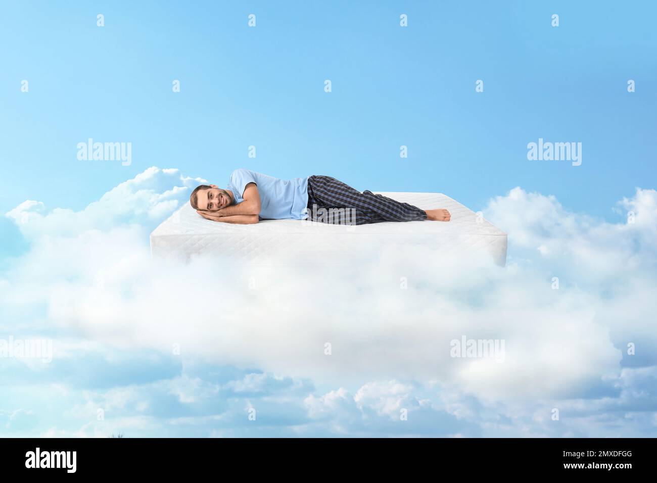 Young man lying on mattress in clouds Stock Photo