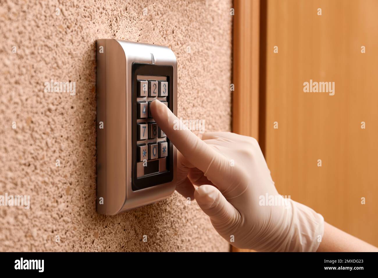 Woman in gloves entering code on electronic lock's keypad indoors, closeup Stock Photo