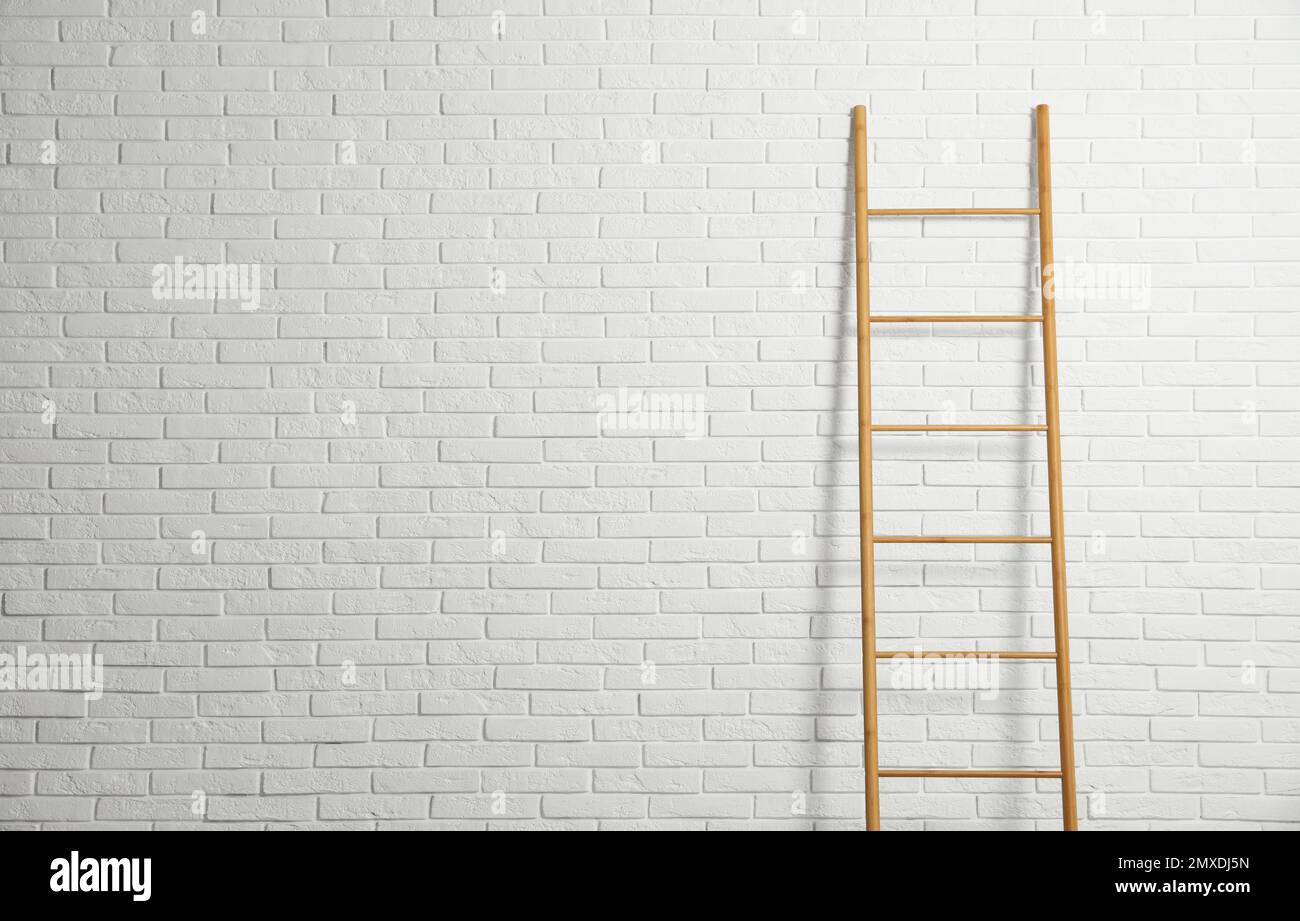 Modern wooden ladder near white brick wall. Space for text Stock Photo ...
