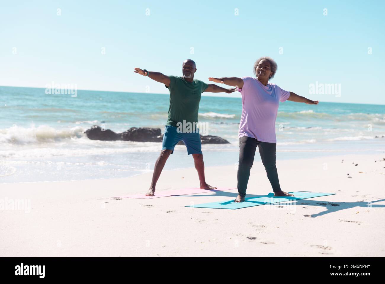 African american senior couple practicing warrior 2 pose on yoga mats ...