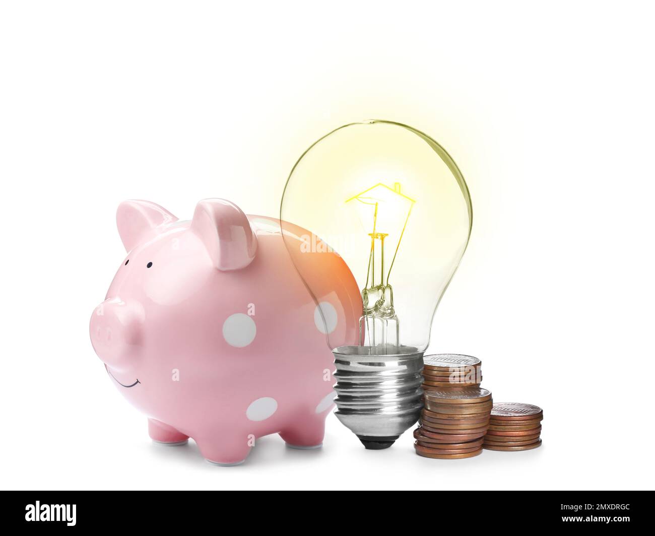Light bulb with tungsten filament in shape on house roof, piggy bank and coins on white background. Energy efficiency, loan, property or business idea Stock Photo
