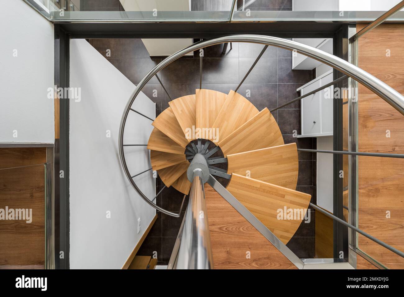 Modern spiral staircase with wooden steps and metal railings looking down from above creates a feeling of weightlessness. Stylish staircase with Stock Photo