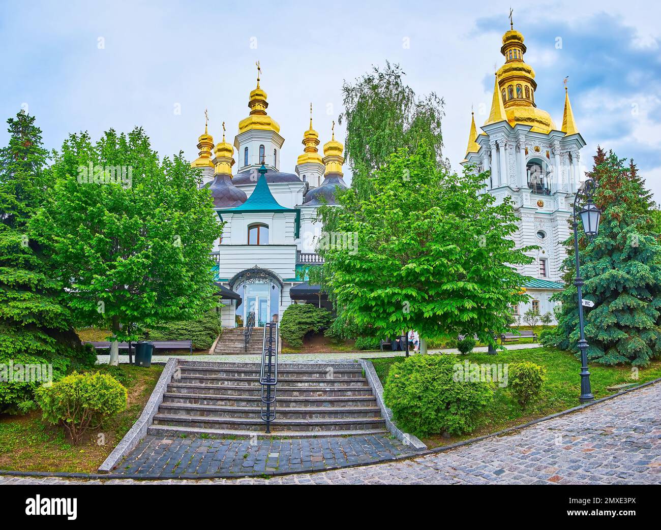 Historic Nativity Church, topped with golden domes, behind the lush green park, Kyiv Pechersk Lavra Cave Monastery, Ukraine Stock Photo