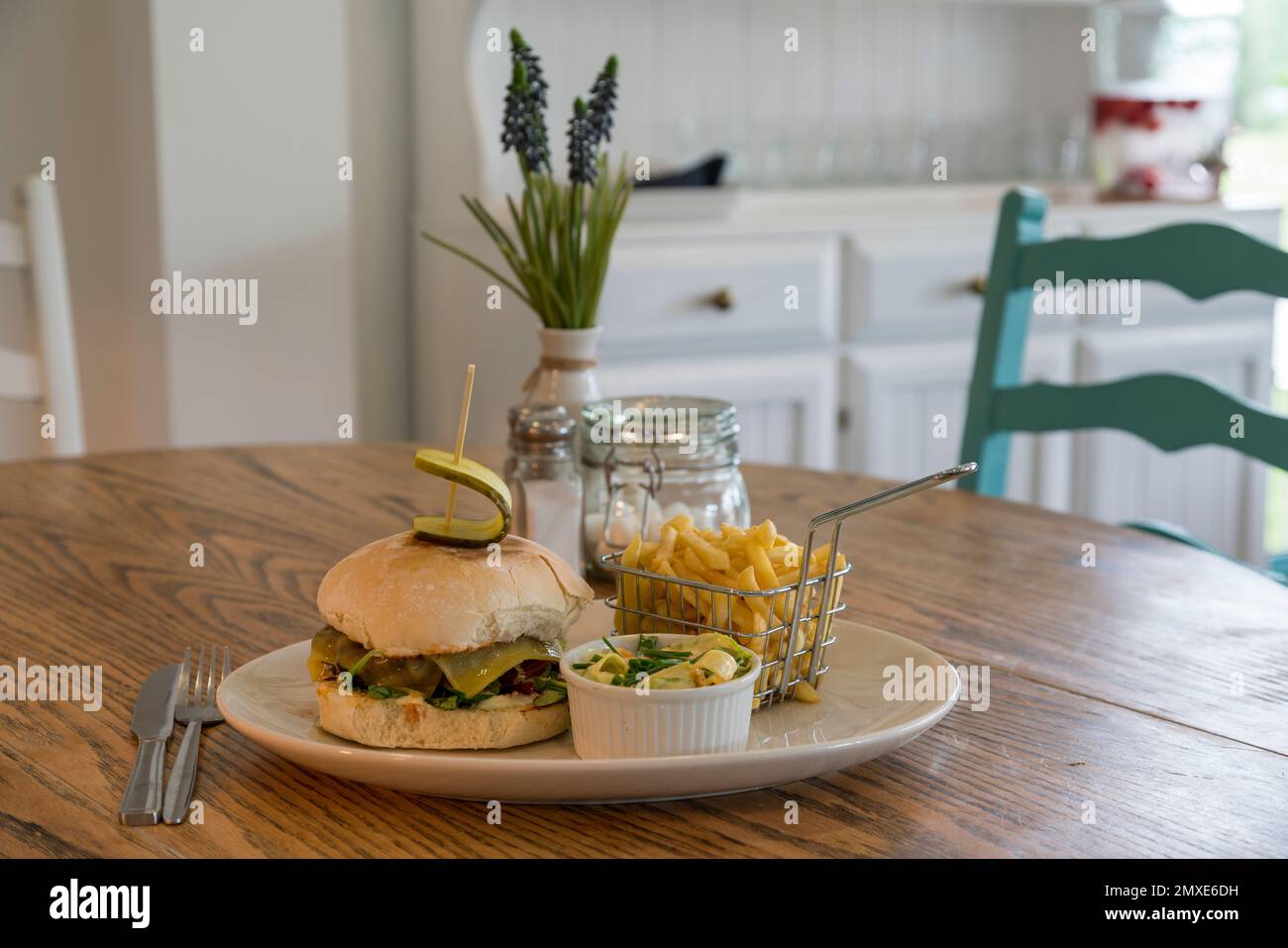 Cafe interior hamburger with chips and coleslaw served on a white plate Stock Photo