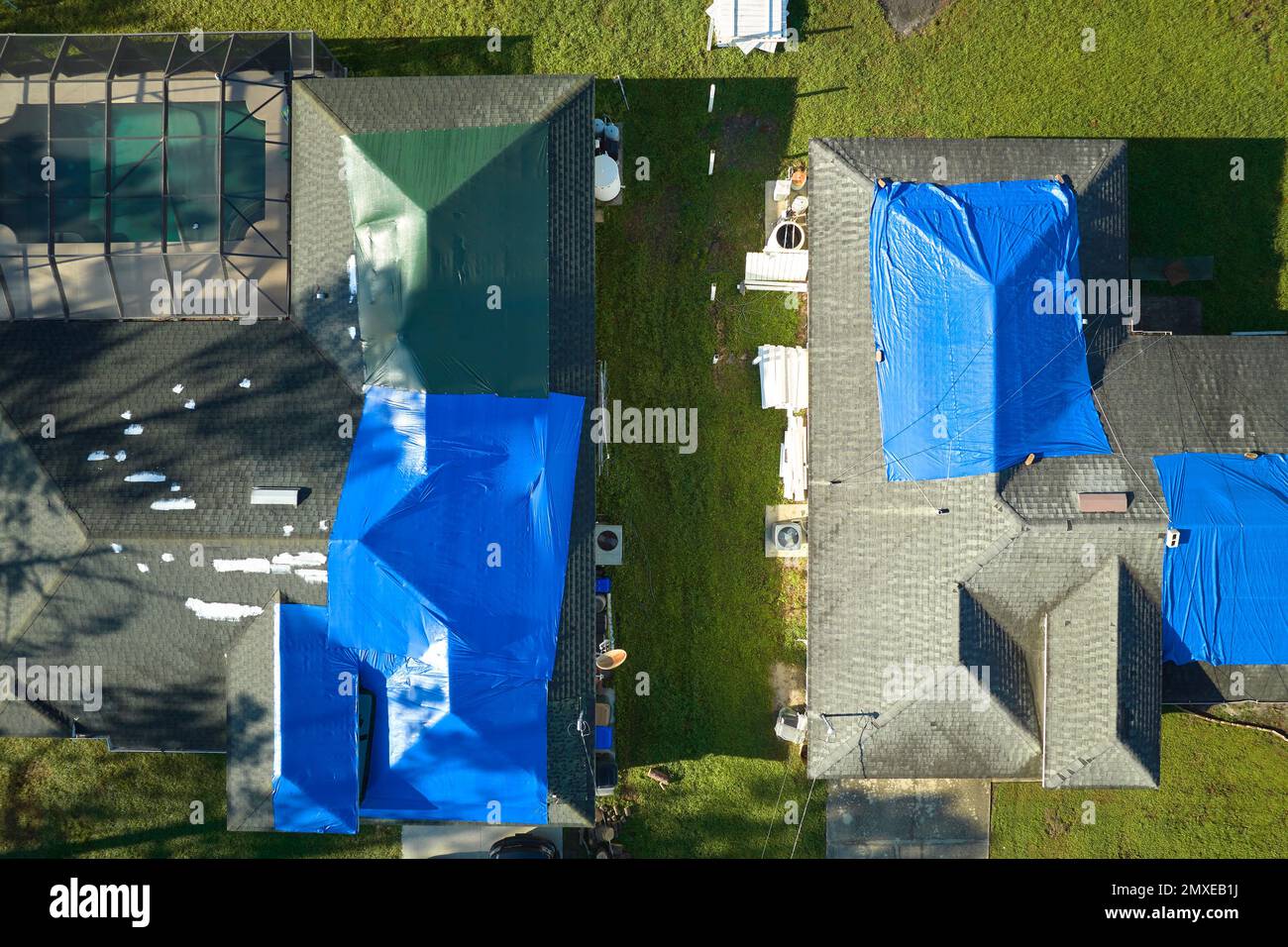 Aerial view of damaged in hurricane Ian house roof covered with blue