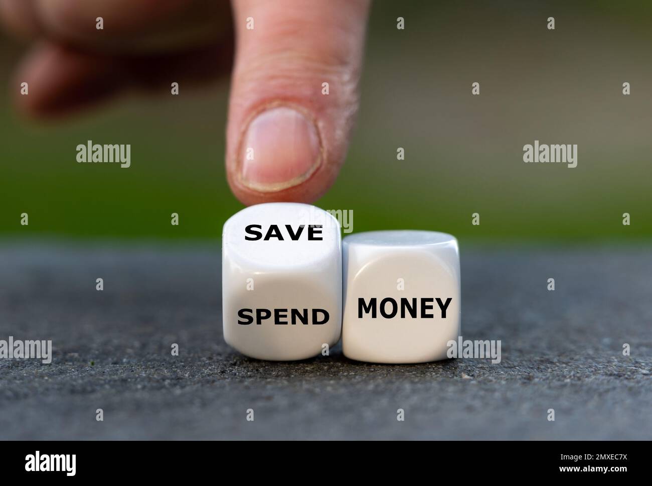 Hand turns dice and changes the expression 'spend money' to 'save money'. Stock Photo