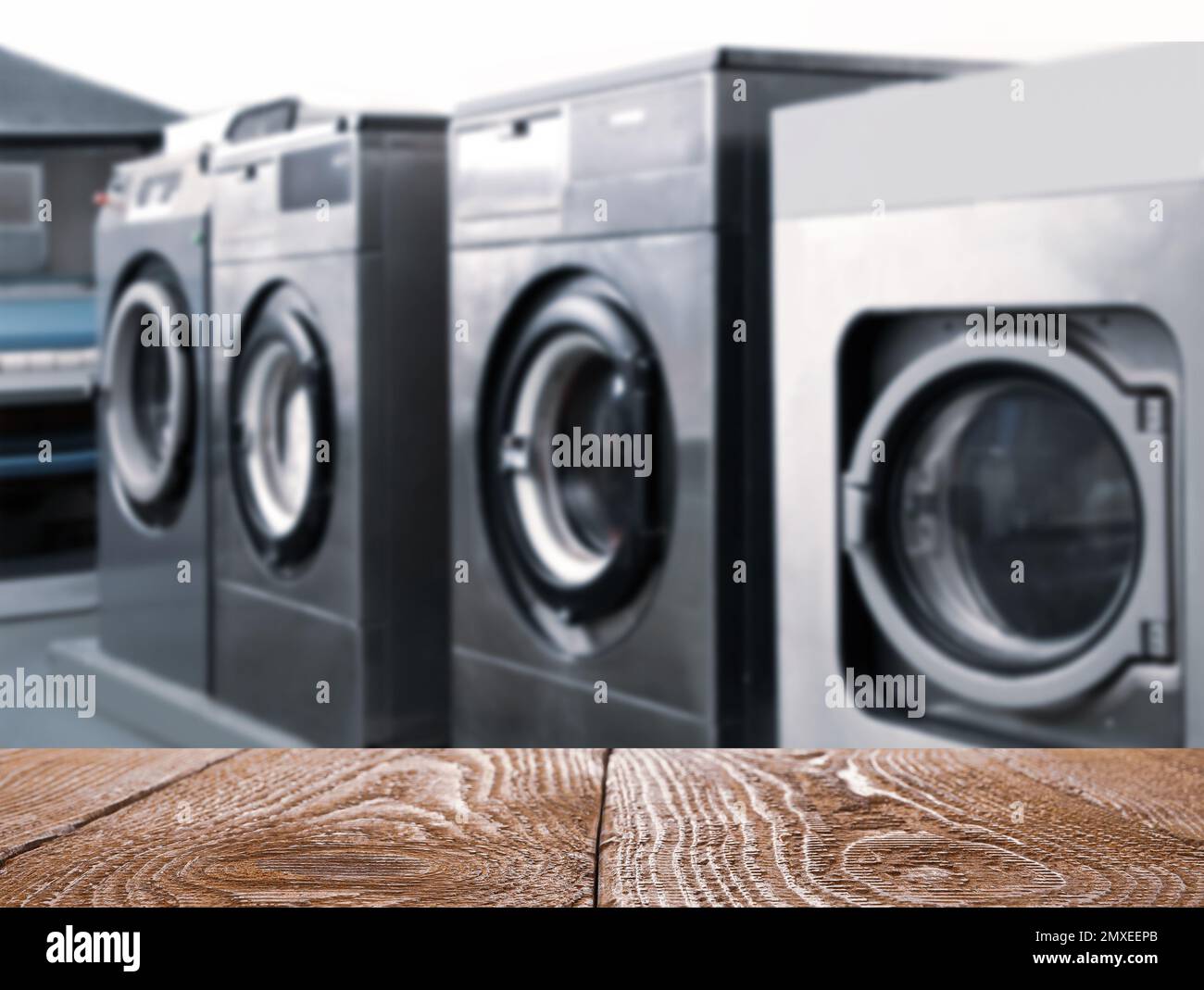 Empty wooden surface and modern washing machines in dry-cleaning, space for text Stock Photo