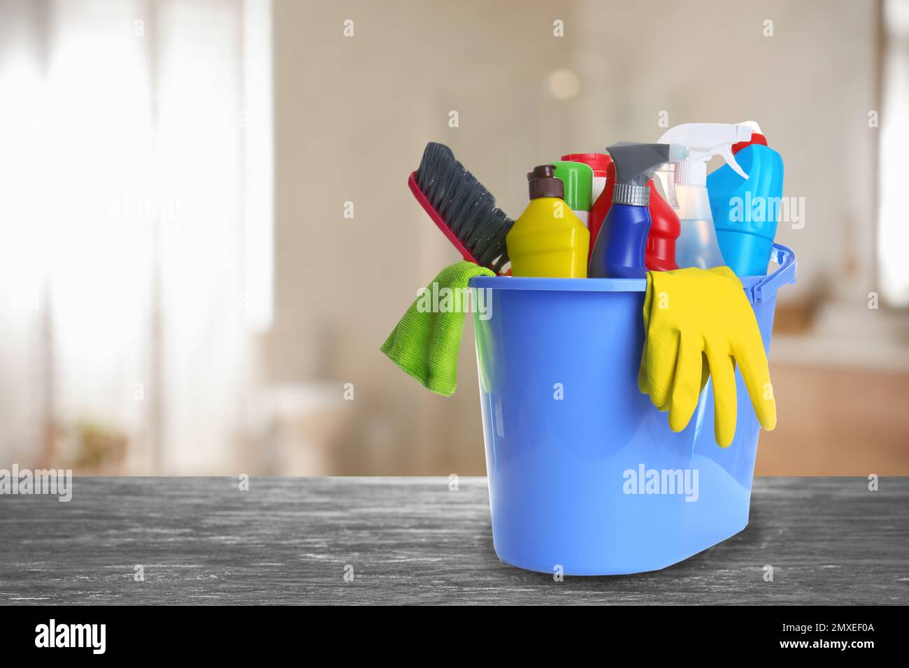 Bucket with cleaning supplies on stone surface in modern room. Space