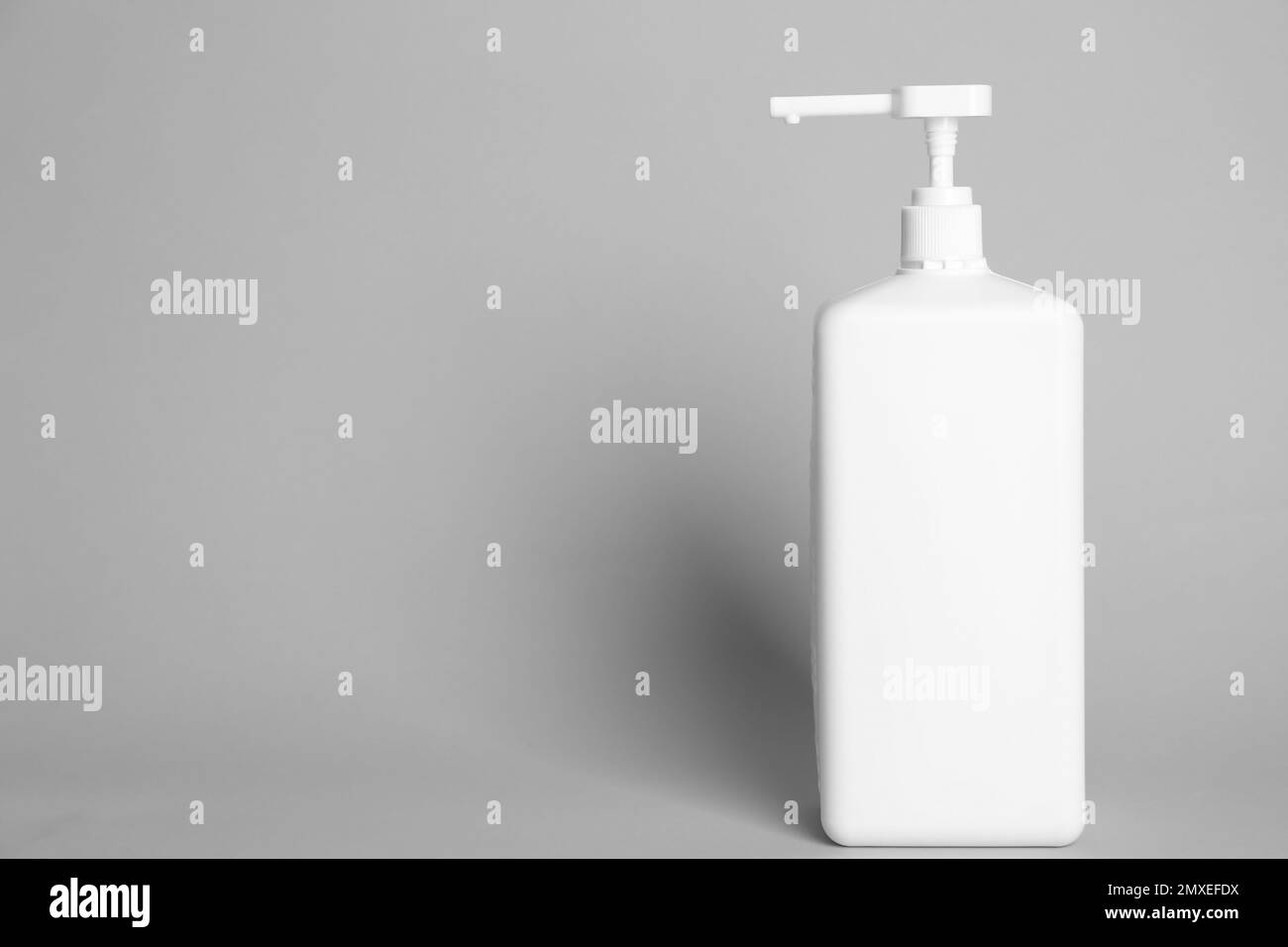 Dispenser bottle with antiseptic gel on light grey background. Space