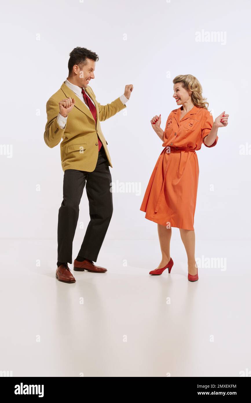 Stylish smiling man and woman in retro style clothes dancing twist dance isolated over white background. Concept of love, relationship, retro style Stock Photo