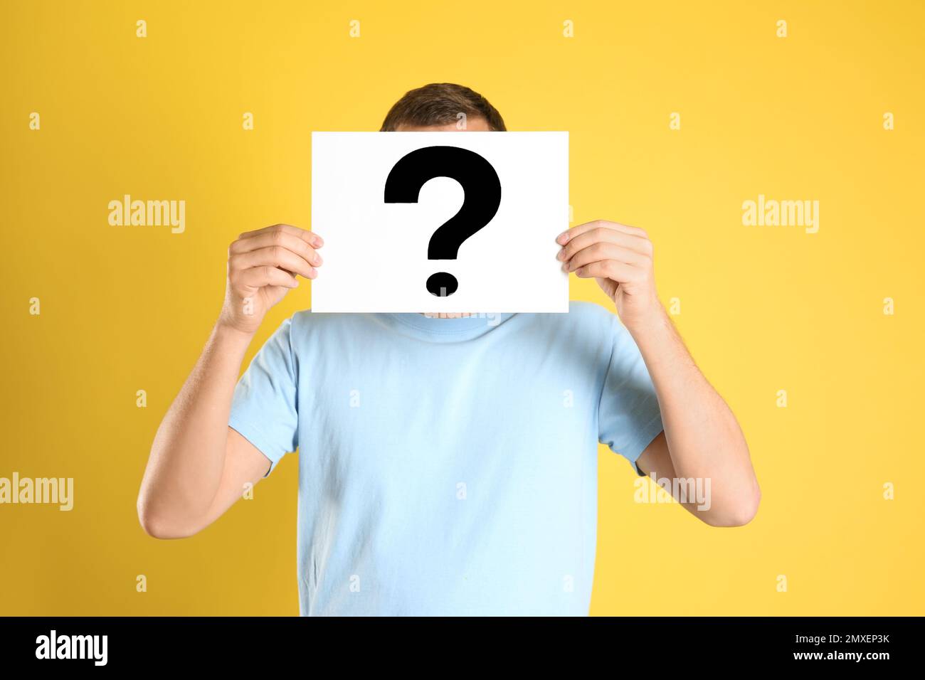 Man holding paper with question mark on yellow background Stock Photo ...