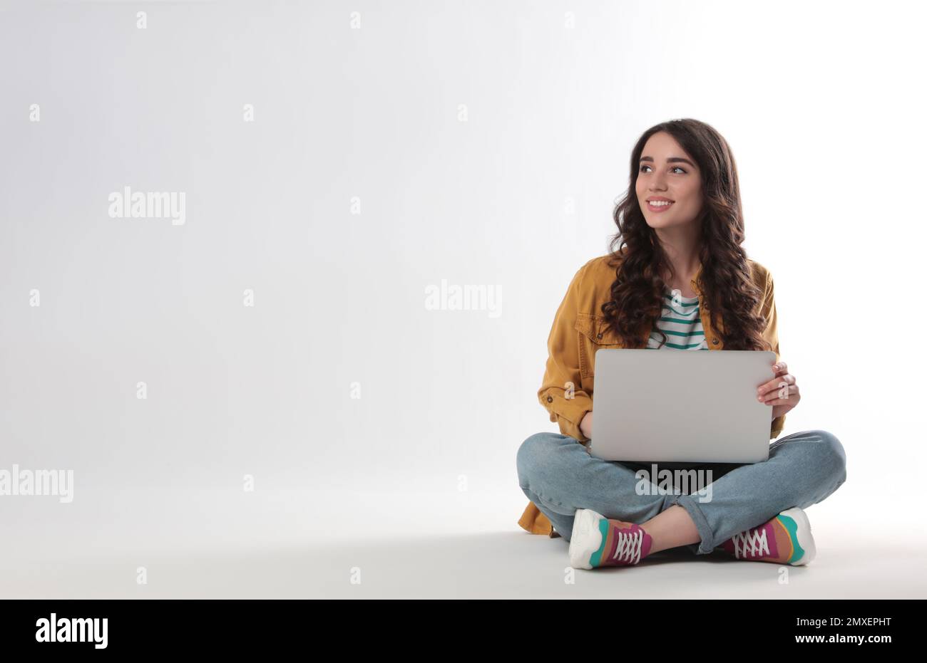 Young woman sitting with laptop on white background Stock Photo - Alamy