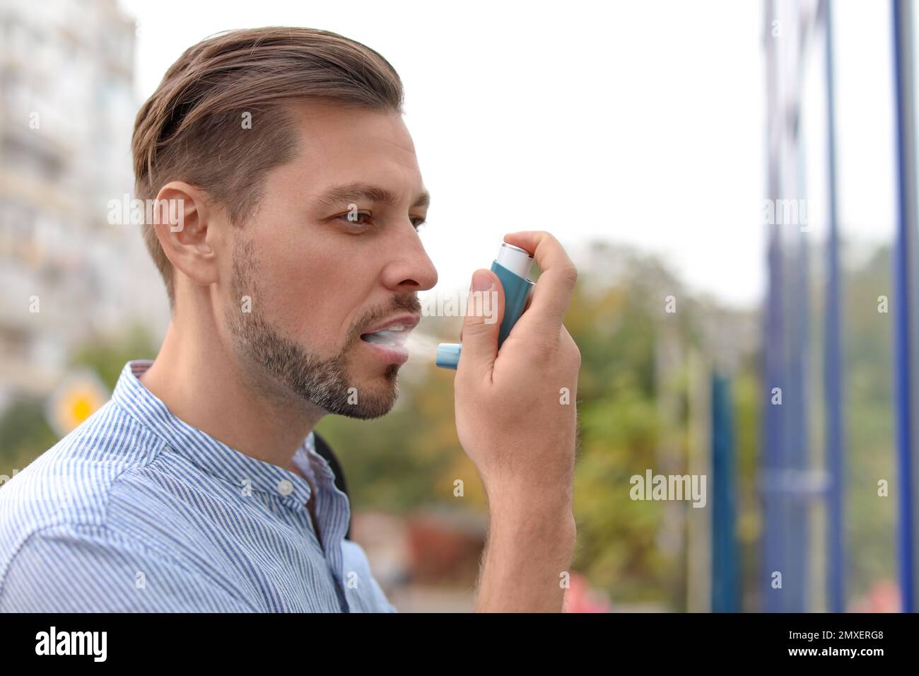 Man using asthma inhaler outdoors. Health care Stock Photo