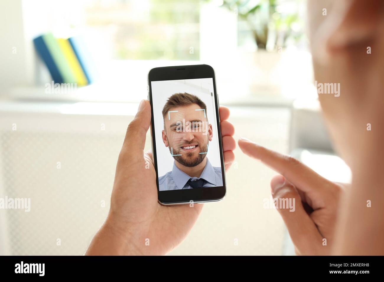 Man using smartphone with facial recognition system indoors, closeup. Biometric verification Stock Photo