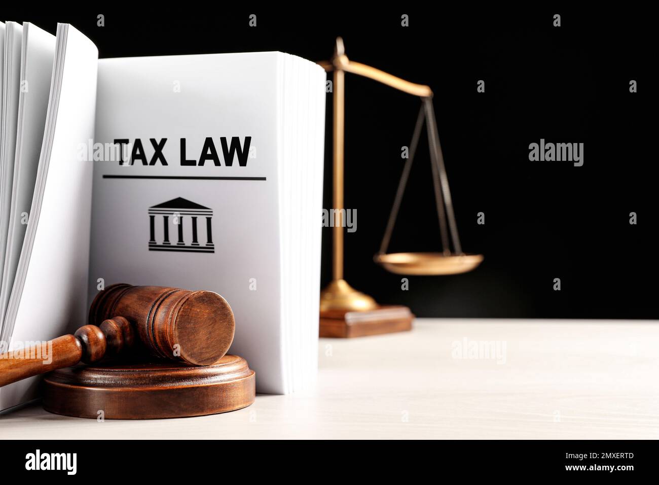 Tax law book, judge's gavel and scales on white table against black background. Space for text Stock Photo