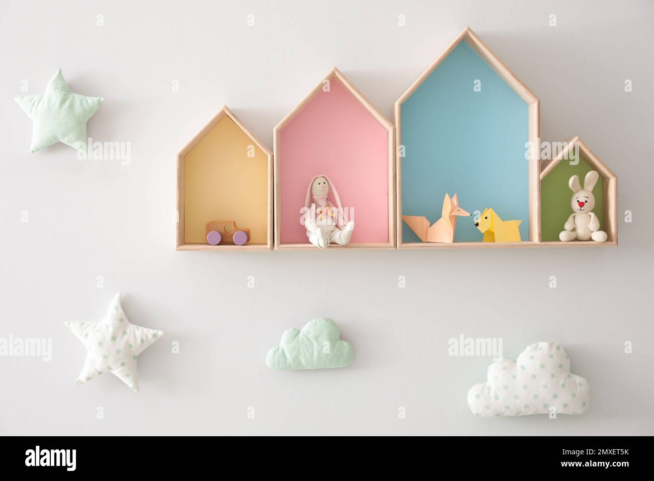 Different house shaped shelves with toys and decorative clouds on white