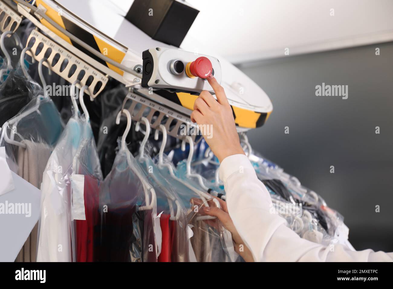 Worker pressing button on control panel of garment conveyor at modern