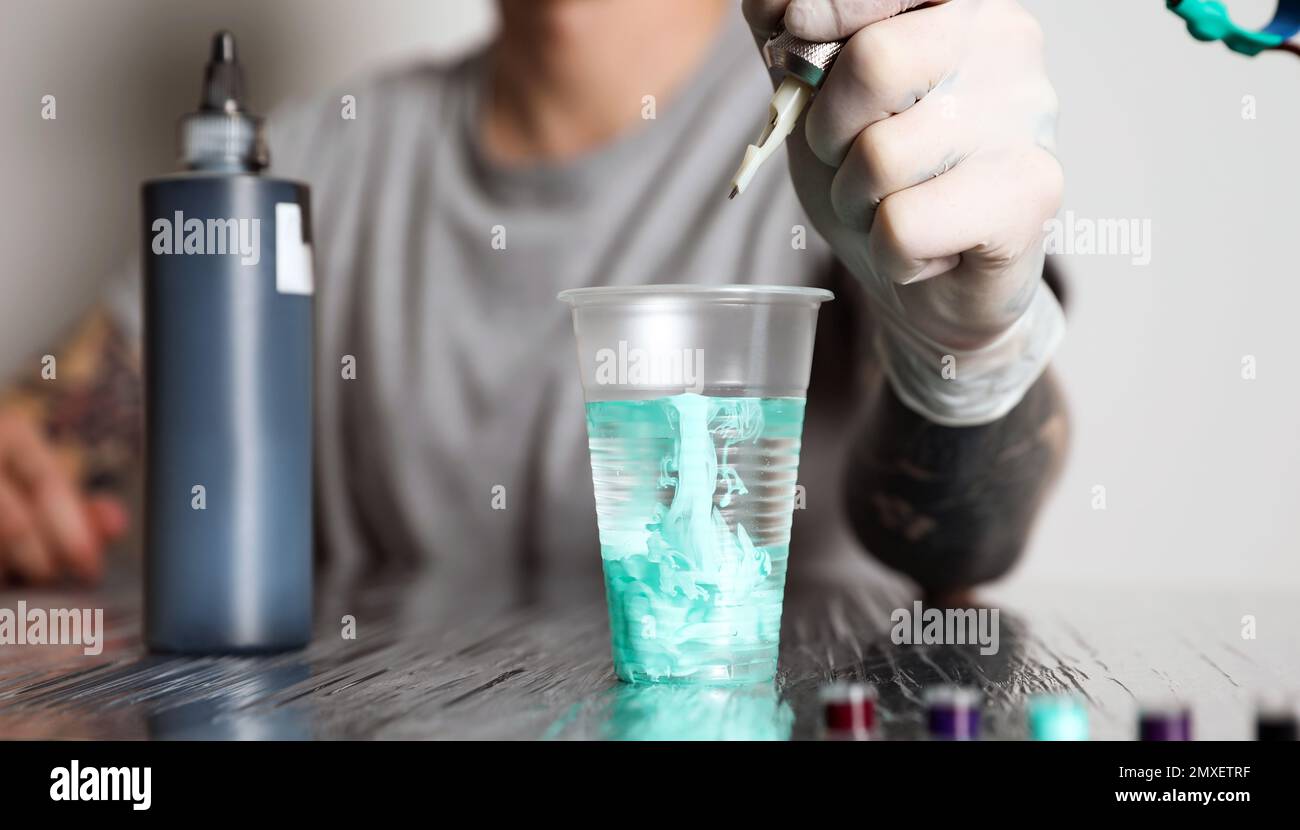 Tattoo artist cleaning machine needle at table, closeup Stock Photo Alamy
