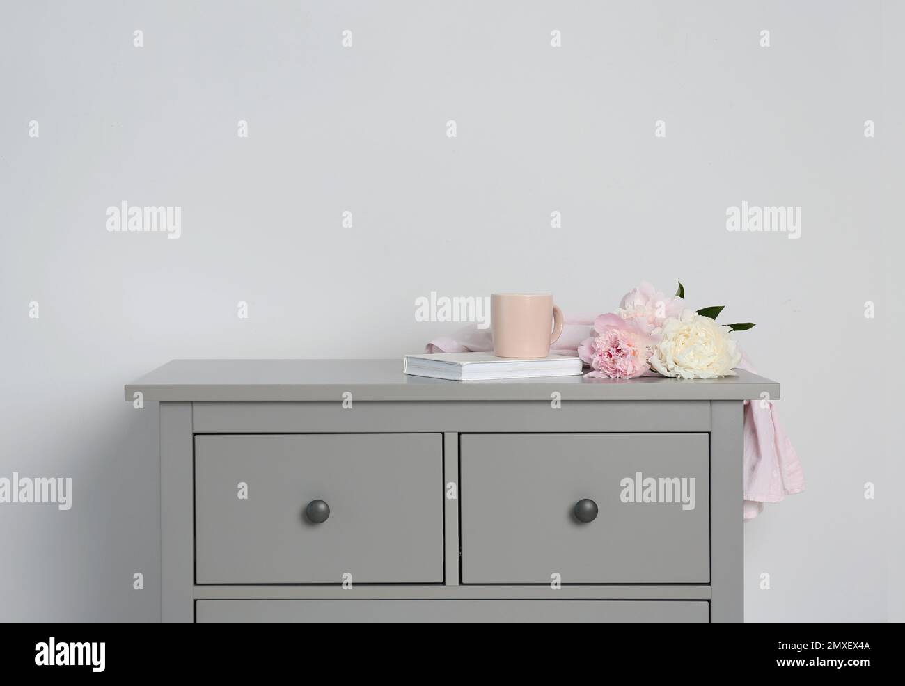 Grey chest of drawers on light background Stock Photo - Alamy