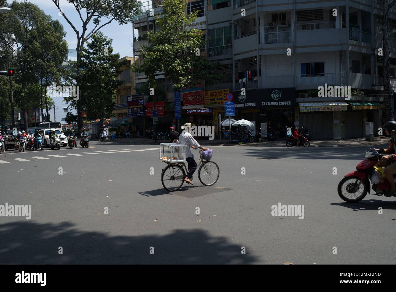 A lone cyclist crossing the road in Ho Chi Min Stock Photo
