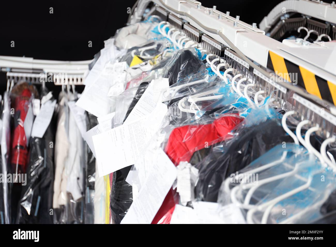 Hangers with clothes on garment conveyor at drycleaner's Stock Photo