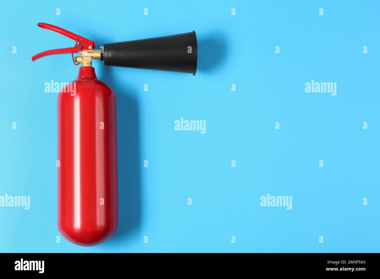 Fire extinguisher on light blue background, top view. Space for text