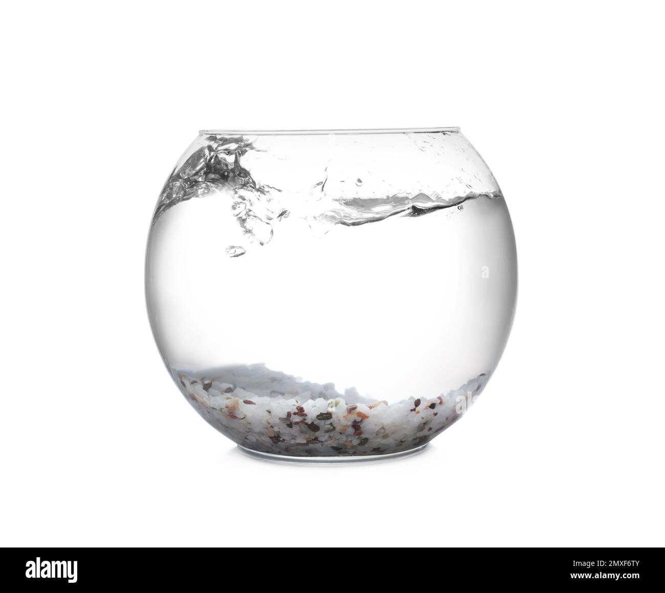 Splash of water in round fish bowl with decorative pebbles on white