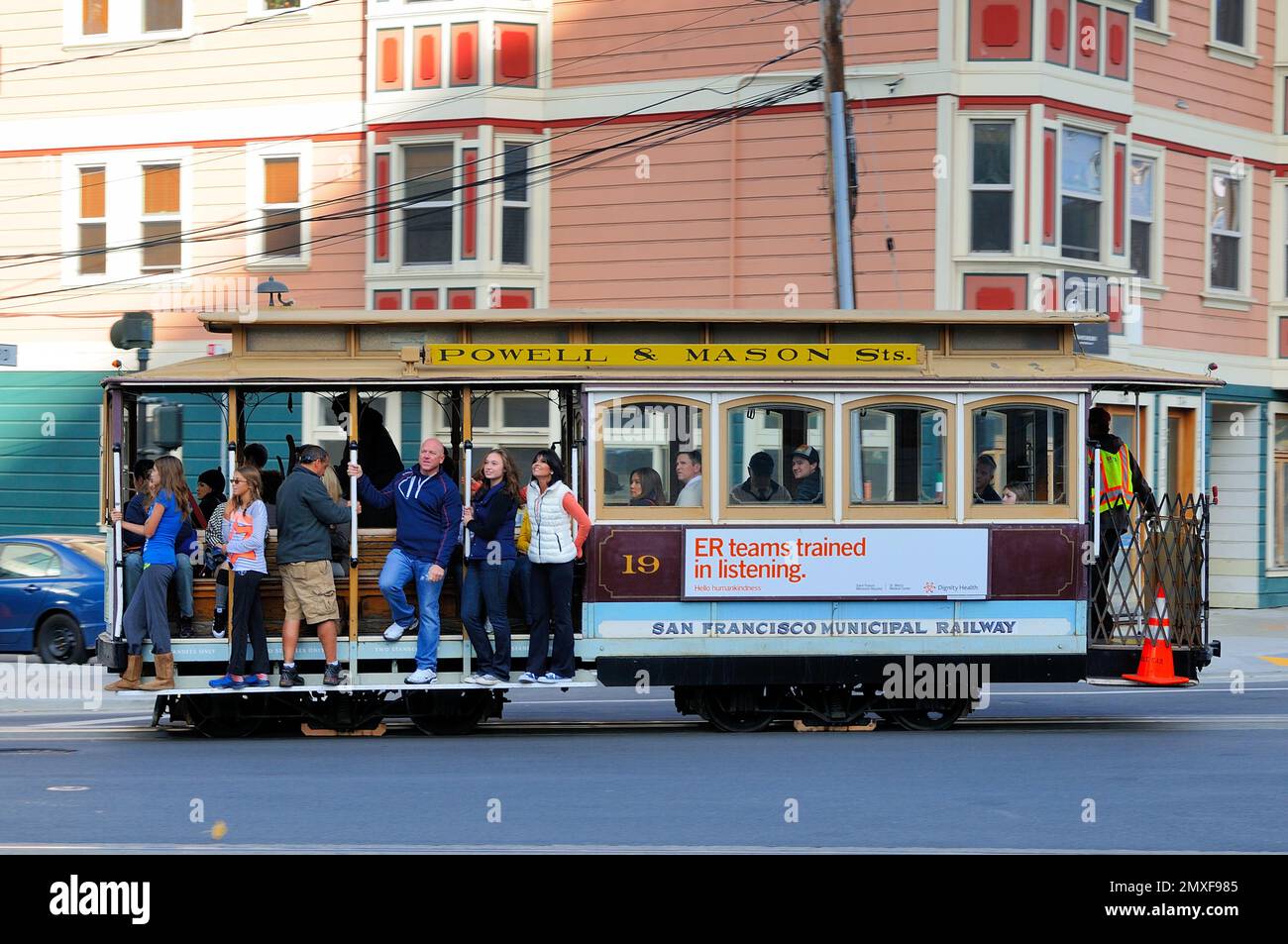 Cable car charm: City rides with passengers, vibrant architecture, and urban energy. Stock Photo