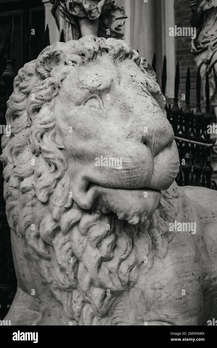 A vertical shot of an ancient statue of a lion in black and white Stock