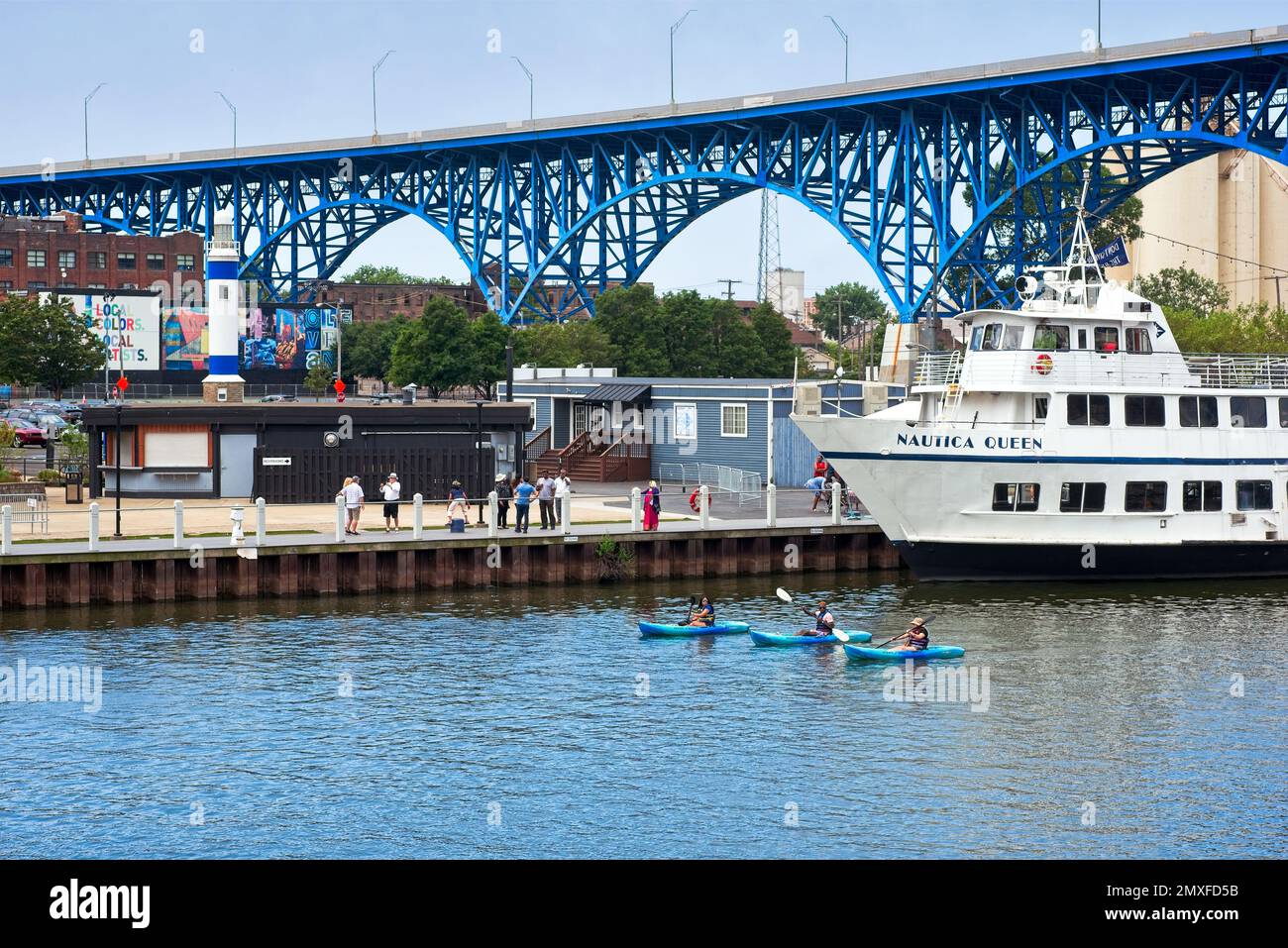 Three kayakers paddle past the Nautica Queen, a popular excursion boat