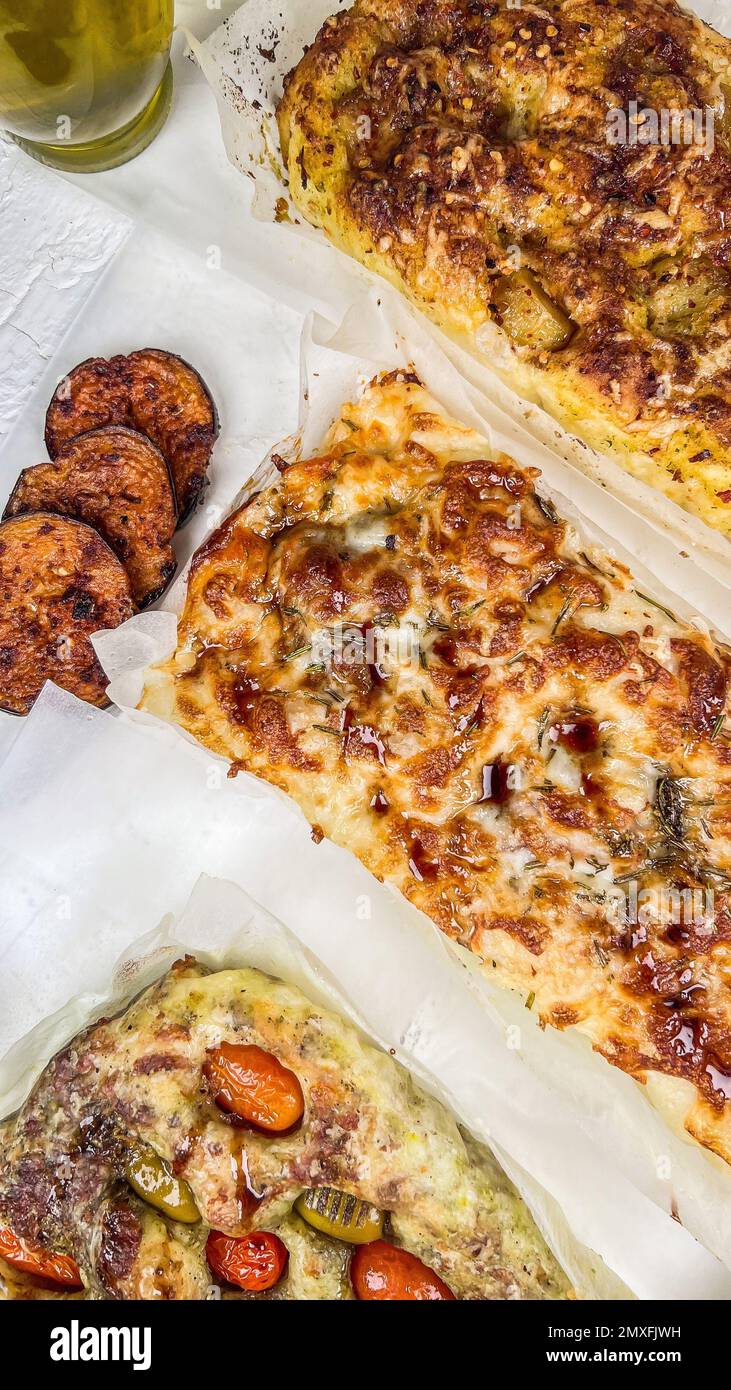 A top view of sliced pizzas on chopping board with oil around Stock Photo
