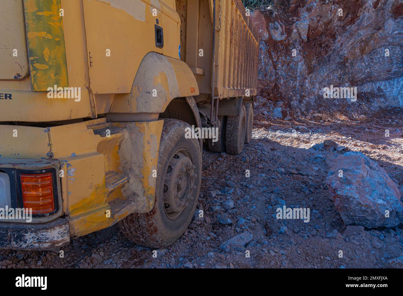 Heavy machinery works at the construction site. Clearing rocky soil for construction in Turkey. Wheels of a vintage yellow truck. Stock Photo