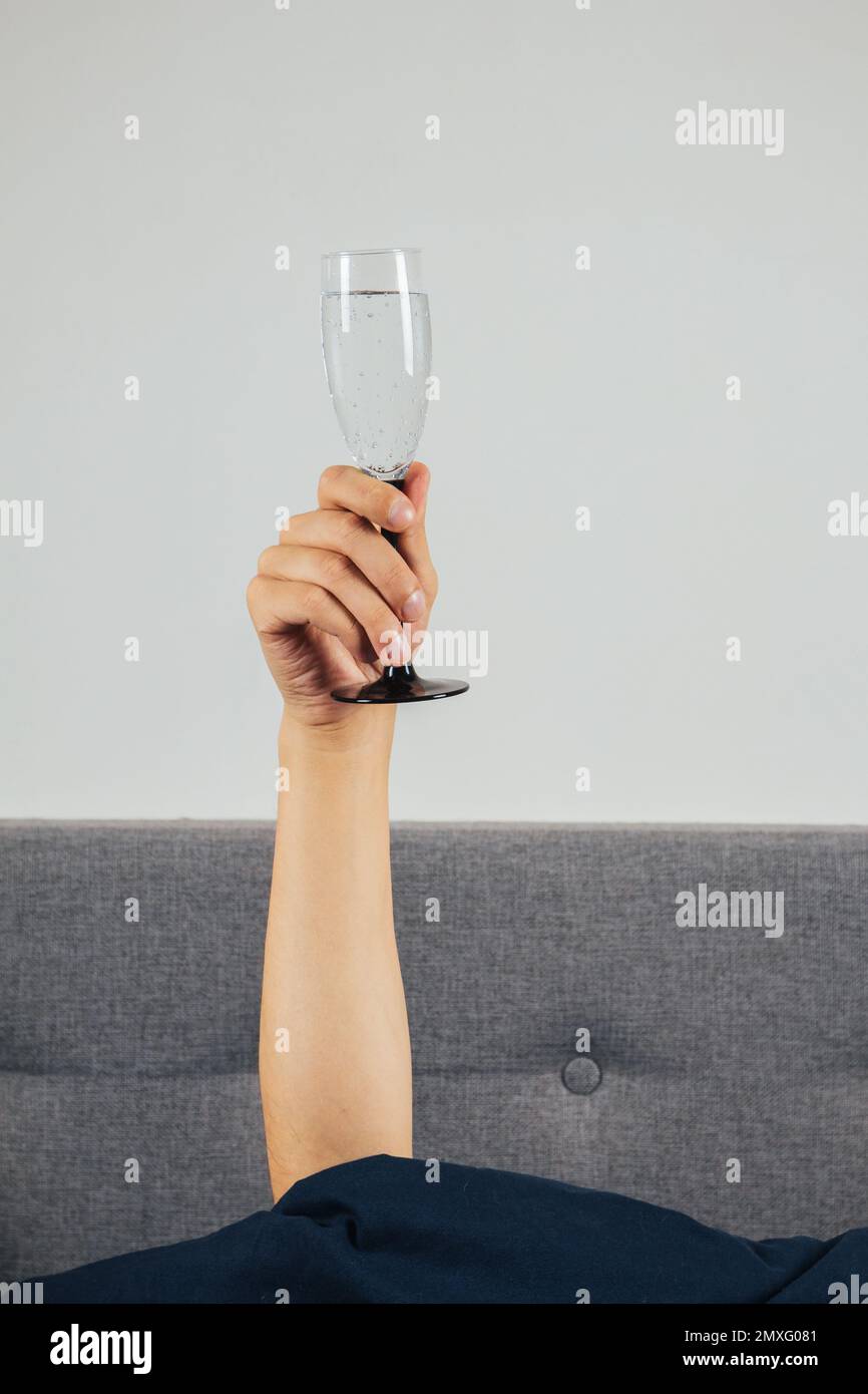 Champagne in a man's hand in bed. Hangover, alcohol intoxication