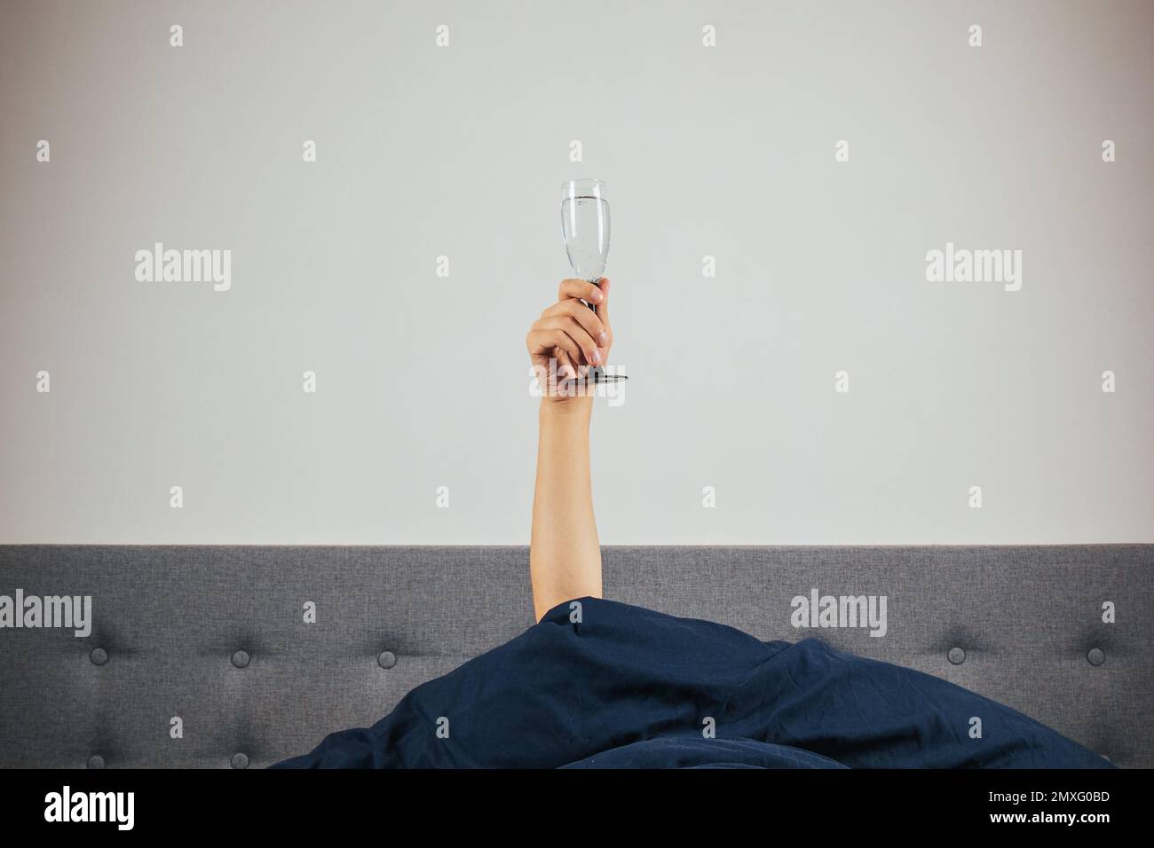 Champagne in a man's hand in bed. Hangover, alcohol intoxication