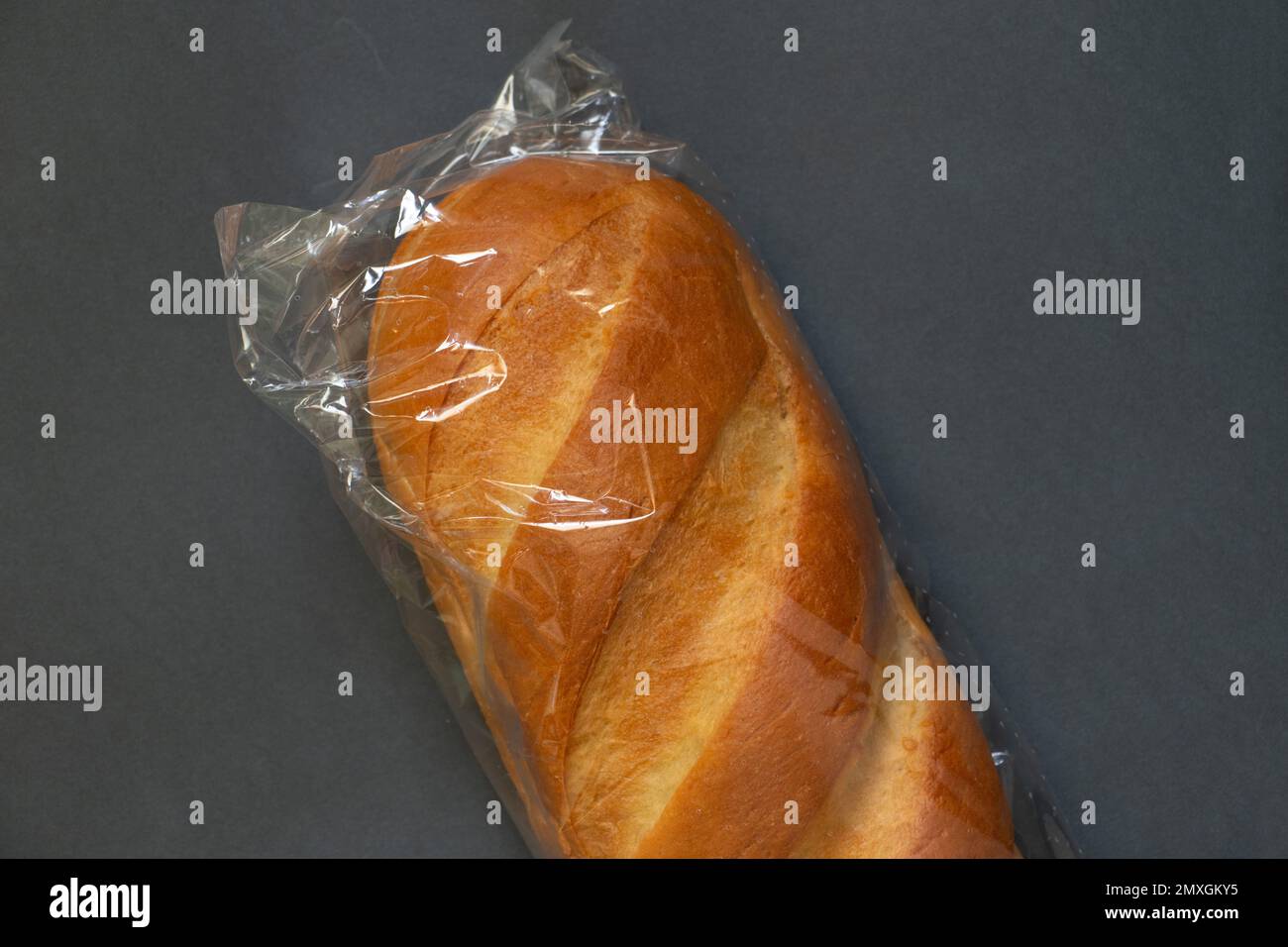 loaf of white bread in packaging on a dark isolated background close-up Stock Photo