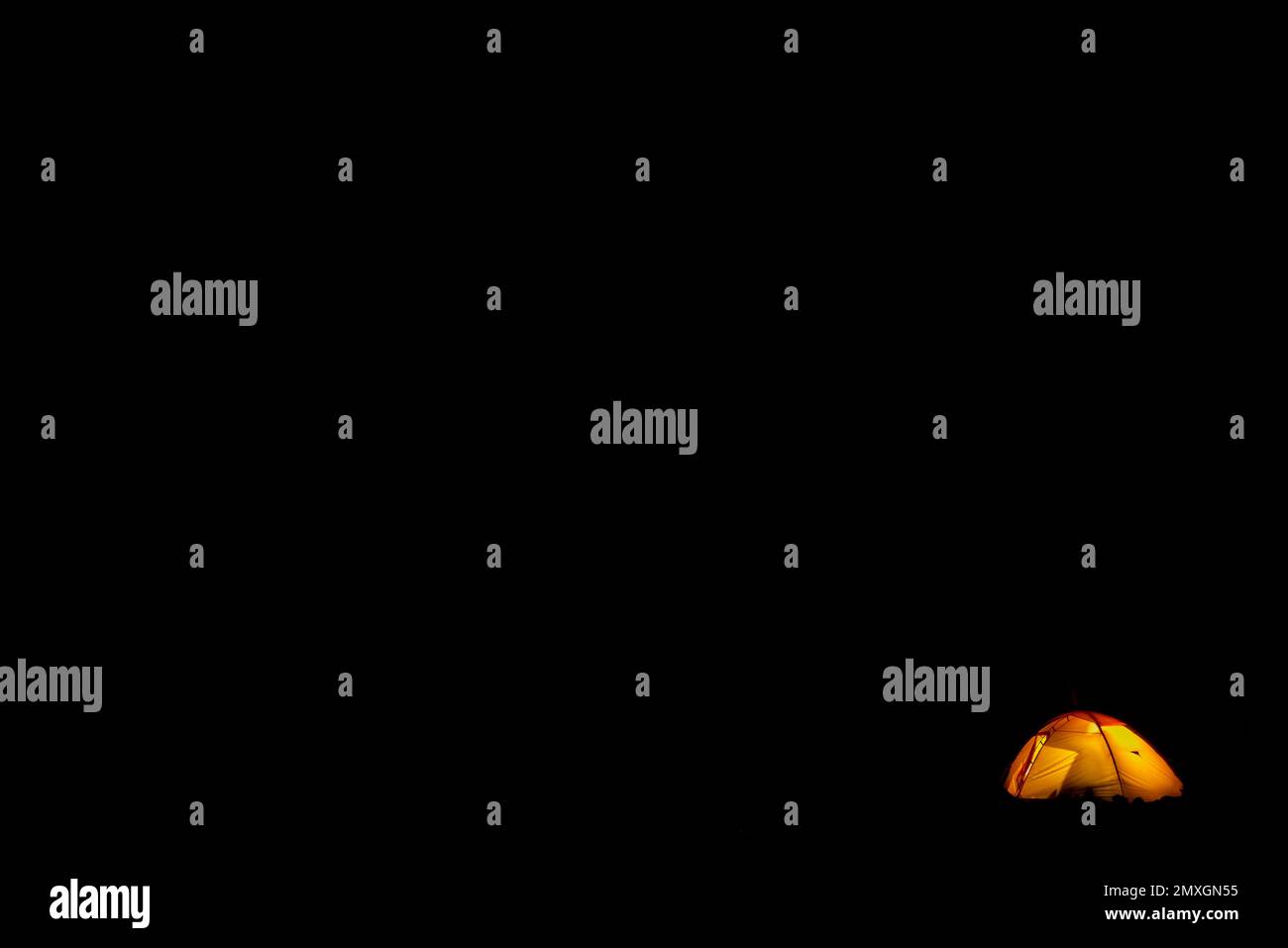 The travelers' orange tourist tent glows in complete darkness Stock